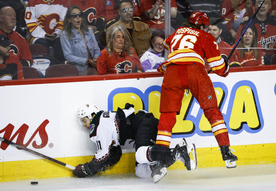 Arizona Coyotes forward Dylan Guenther (11) is checked by Calgary Flames forward Martin Pospisil (76) during the first period of an NHL hockey game in Calgary, Alberta, Sunday, April 14, 2024. (Jeff McIntosh/The Canadian Press via AP)