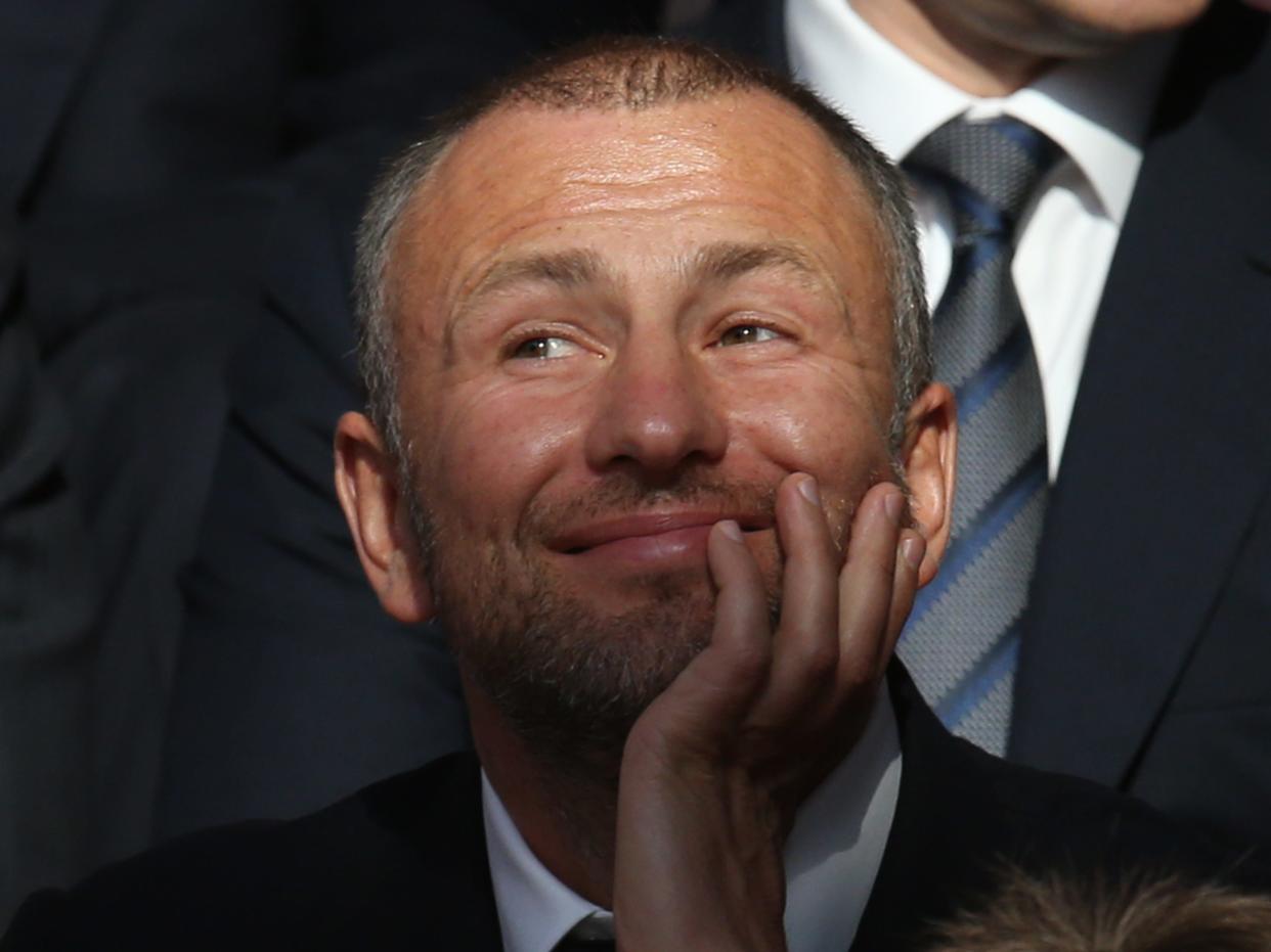 A picture of Andrey Melnichenko smiling with his hands on his chin.
