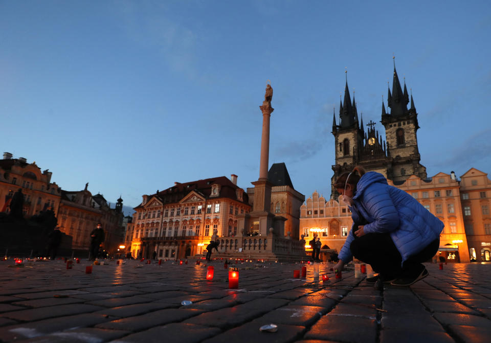 A woman lights up a candle to pay respect to victims of the COVID-19 pandemic at a spontaneous memorial place set at the Old Town Square in Prague, Czech Republic, Monday, March 29, 2021. The coronavirus pandemic is unleashing enormous suffering as infection rates rise across central Europe even as the Czech Republic and Slovakia, recently among the worst-hit areas in the world, are finally seeing some improvements following tight lockdowns. (AP Photo/Petr David Josek)