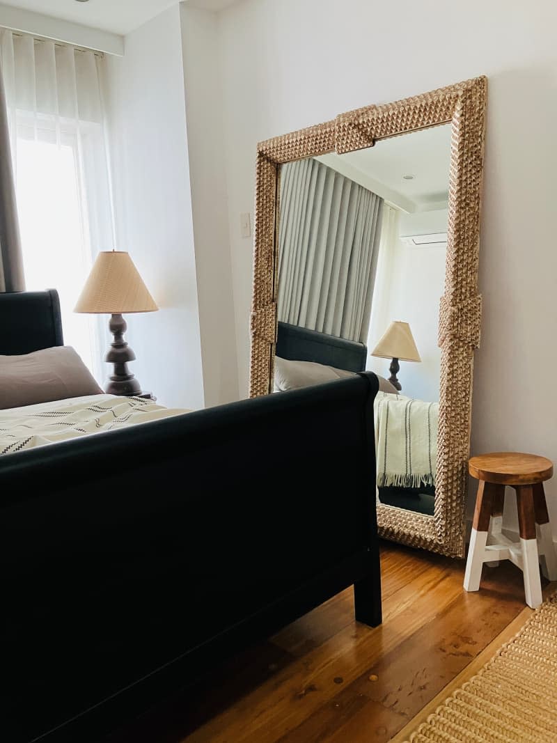 Wicker framed floor length mirror in bedroom.