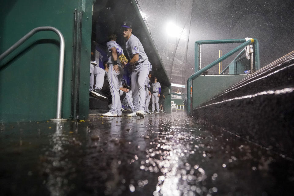 Colorado Rockies players avoid the rain in the dugout during a rain delay in the seventh inning of a baseball game against the Washington Nationals at Nationals Park, Tuesday, July 25, 2023, in Washington. (AP Photo/Alex Brandon)