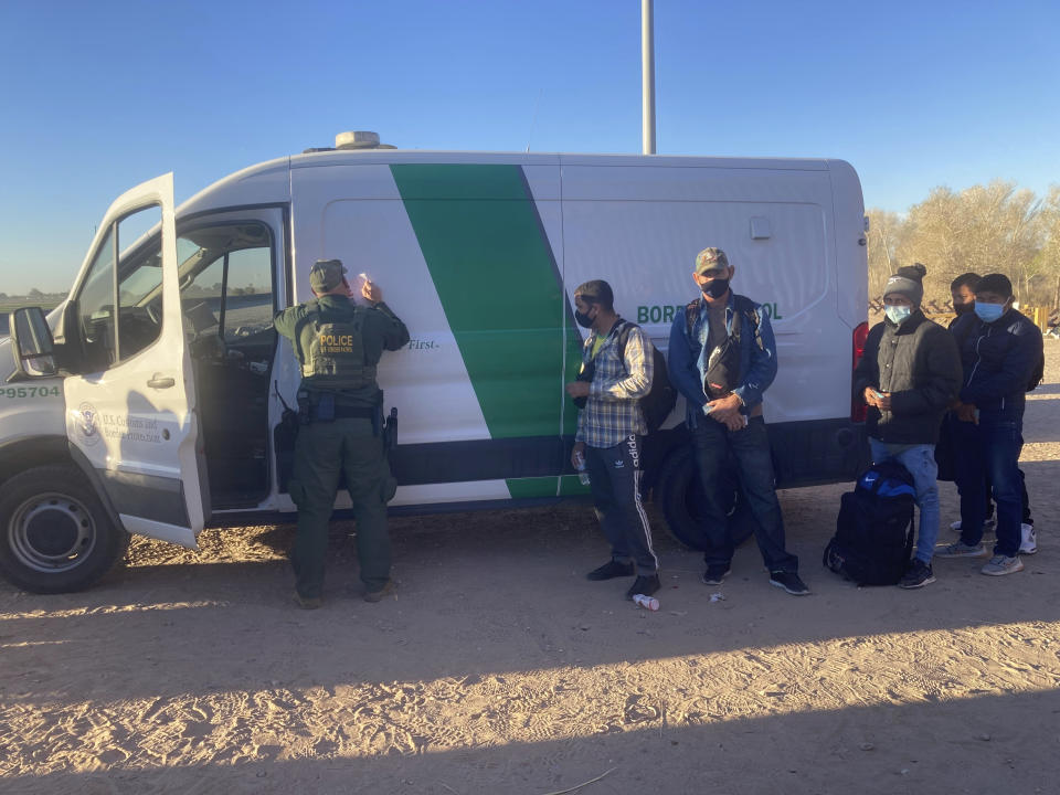 A Border Patrol agent fills out paperwork for migrants who surrendered in Yuma, Ariz., Saturday, Feb. 5, 2022, after crossing the border illegally from Los Algodones, Mexico. For nationalities that don't need a visa, Mexico is often the ticket to seeking asylum in the United States. (AP Photo/Elliot Spagat)