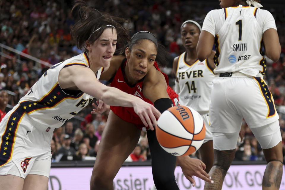 Indiana Fever guard Caitlin Clark, left, and Las Vegas Aces center A'ja Wilson, center, vie for a loose ball during the first half of a WNBA basketball game Tuesday, July 2, 2024, in Las Vegas. (Ellen Schmidt/Las Vegas Review-Journal via AP)