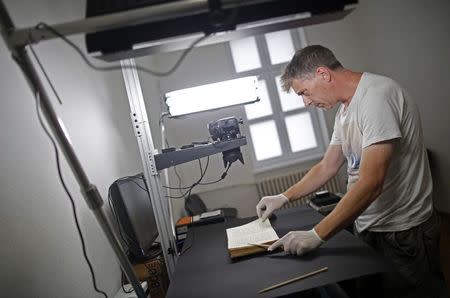 Photographer Jim Marshall, a member of the Foundation for the Preservation of Historical Heritage, photographs pages of a book in Bosnia's National Library in Sarajevo August 19, 2014. REUTERS/Dado Ruvic