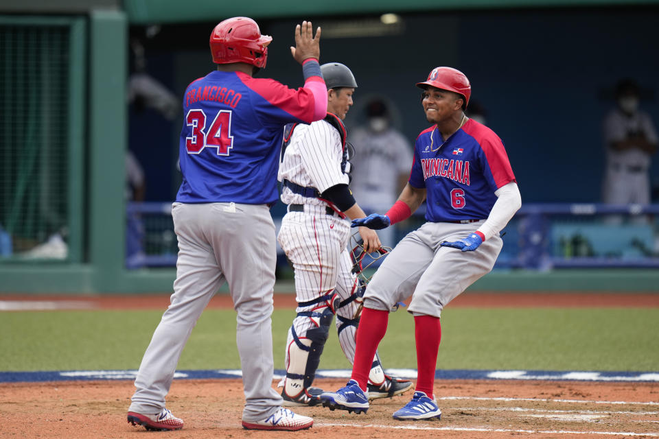 Dominican Republic's Erick Mejia(6) and Juan Francisco (34) celebrate after they scored on a double hit by Charlie Valerio during the seventh inning of a baseball game against Japan at the 2020 Summer Olympics, Wednesday, July 28, 2021, in Fukushima, Japan. (AP Photo/Jae C. Hong)