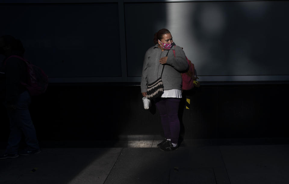 A woman wearing a mask to curb the spread of the new coronavirus stands in front of a building on Paseo de la Reforma in Mexico City, Wednesday, June 17, 2020. (AP Photo/Marco Ugarte)