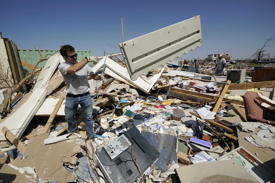 Charlie Weissinger, tosses away the paneling from one of the desks in his father's demolished law office in Rolling Fork, Miss., Saturday, March 25, 2023. Emergency officials in Mississippi say several people have been killed by tornadoes that tore through the state on Friday night, destroying buildings and knocking out power as severe weather produced hail the size of golf balls moved through several southern states. (AP Photo/Rogelio V. Solis)