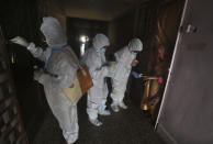 Health workers screen people for COVID-19 symptoms at a residential building in Dharavi, one of Asia's biggest slums, in Mumbai, India, Friday, Aug. 7, 2020. As India hit another grim milestone in the coronavirus pandemic on Friday, crossing 2 million cases and more than 41,000 deaths, community health volunteers went on strike complaining they were ill-equipped to respond to the wave of infection in rural areas. (AP Photo/Rafiq Maqbool)