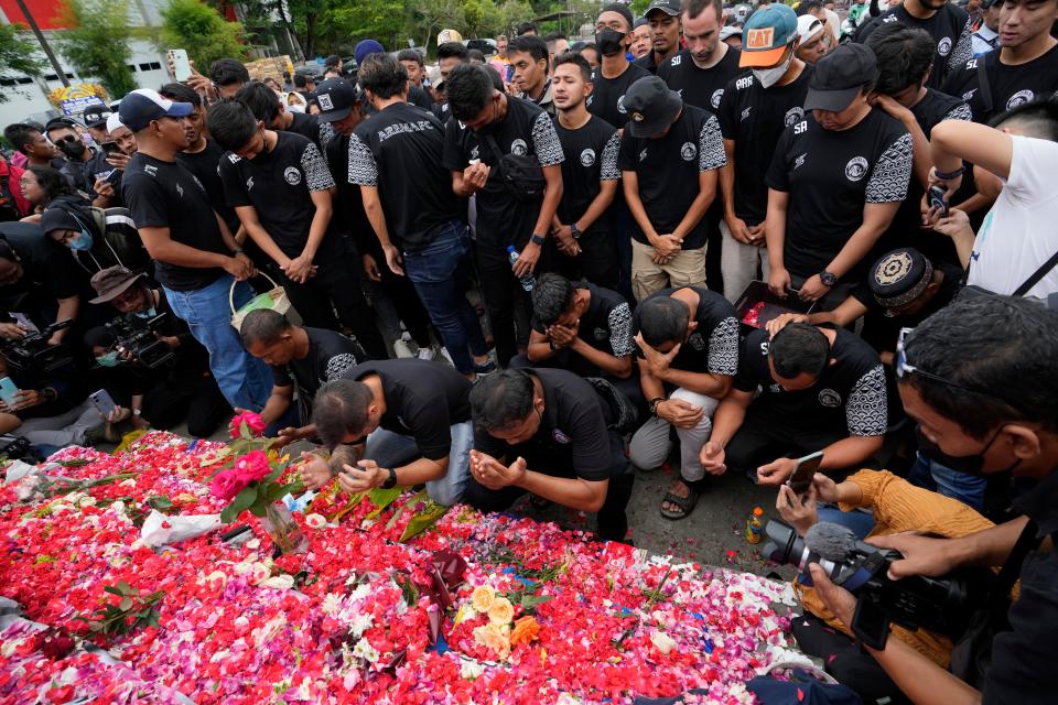 Players and officials of the soccer club Arema FC pray outside the Kanjuruhan Stadium where many fans lost their lives in a stampede Saturday night in Malang, Indonesia, Monday, Oct. 3, 2022.