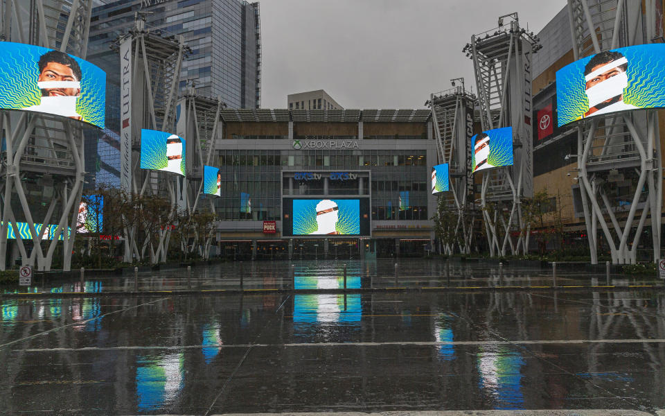 Pantallas de video muestran imágenes de Anthony Davis, jugador de los Lakers de Los Ángeles, en una plaza enfrente del Staples Center, arena donde juegan los Lakers y los Clippers, un equipo de la NHL y uno de la WNBA, en Los Ángeles, el jueves 12 de marzo de 2020. (AP Foto/Damian Dovarganes)