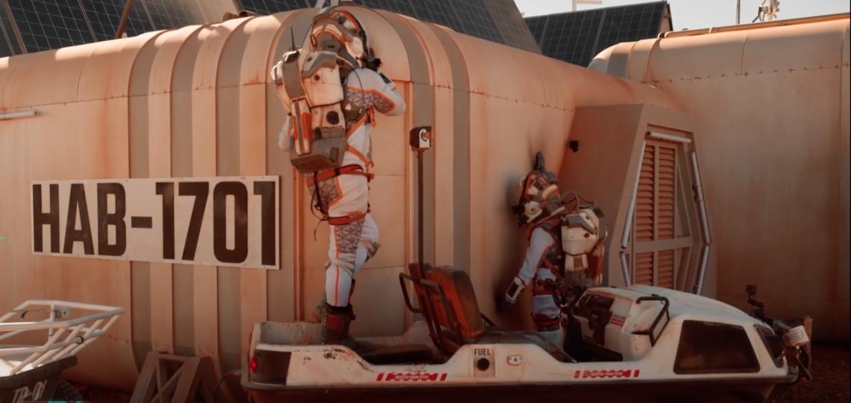  two people in spacesuits work outside a simulated mars habitat 