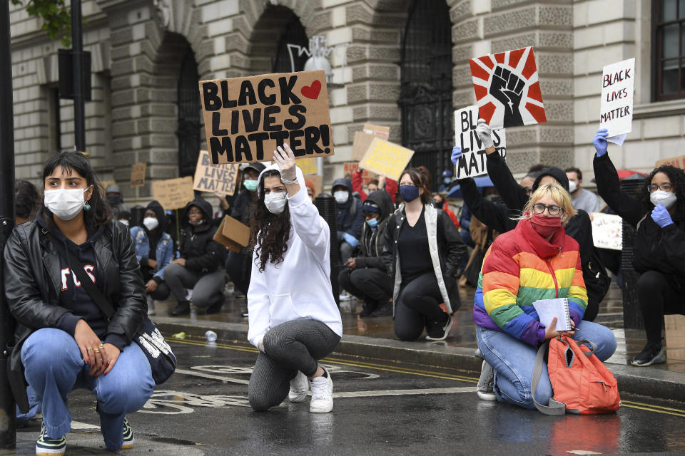 Demonstrators hold placards during a Black Lives Matter rally in Parliament Square in London, Saturday, June 6, 2020, as people protest against the killing of George Floyd by police officers in Minneapolis, USA. Floyd, a black man, died after he was restrained by Minneapolis police while in custody on May 25 in Minnesota. (AP Photo/Alberto Pezzali)