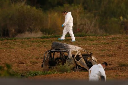 Forensic experts walk in a field after a powerful bomb blew up a car (Foreground) and killed investigative journalist Daphne Caruana Galizia in Bidnija, Malta, October 16, 2017. REUTERS/Darrin Zammit Lupi