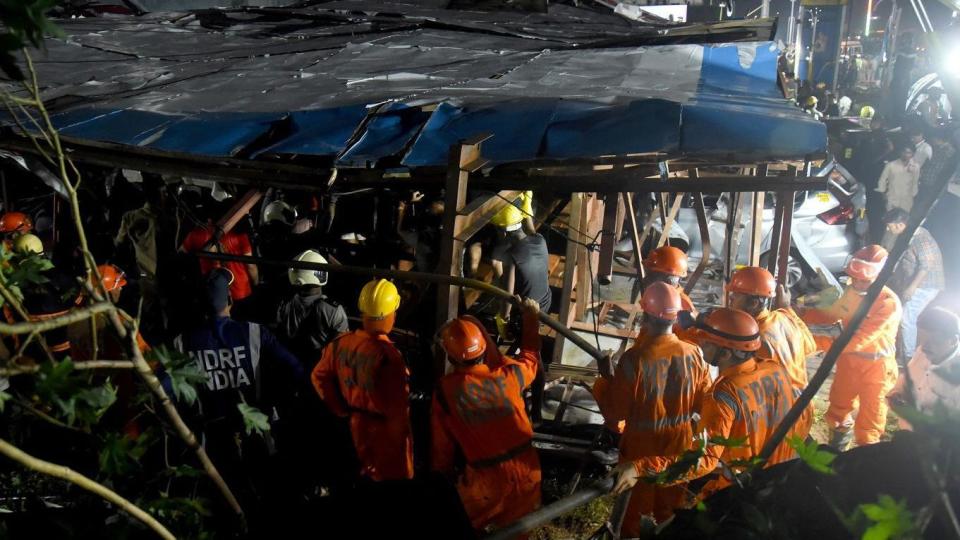 Rescue workers are seen moving through wreckage after a huge billboard blew down in sudden storm in Mumbai, India.