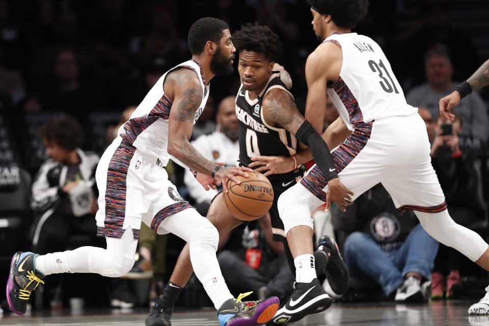 Brooklyn Nets guard Kyrie Irving, left, drives pas Atlanta Hawks guard Brandon Goodwin (0) as Nets center Jarrett Allen (31) defends Parsons during the first half of an NBA basketball game, Sunday, Jan. 12, 2020, in New York. (AP Photo/Kathy Willens)
