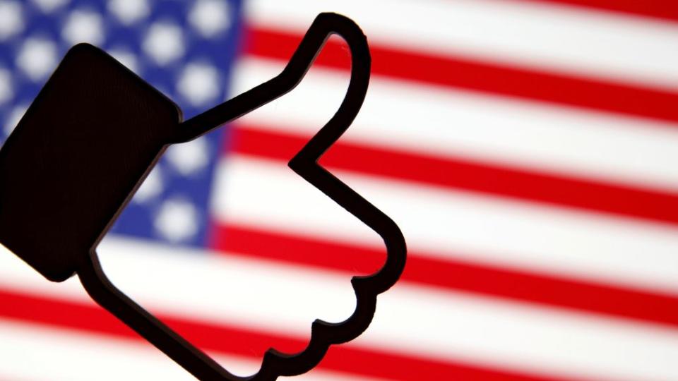 A 3D-printed Facebook Like symbol is displayed in front of a U.S. flag in this illustration