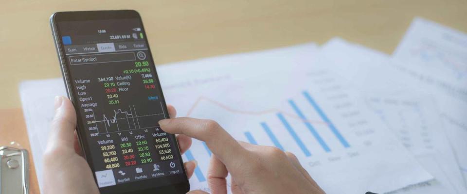 Business women sit and analyze the stock market on the phone The background is a stock graph document top view