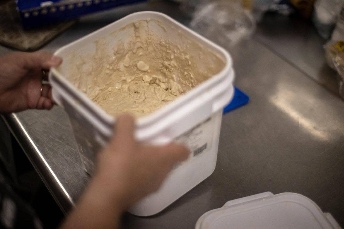 Gwen Johnson lifts a container holding Black Sheep Brick Oven Bakery’s sourdough starter in Hemphill, Ky., on Wednesday, Aug. 31, 2022. Johnson started the bakery in the Hemphill Community Center four years ago as a way to make food locally and give employment to people in recovery.