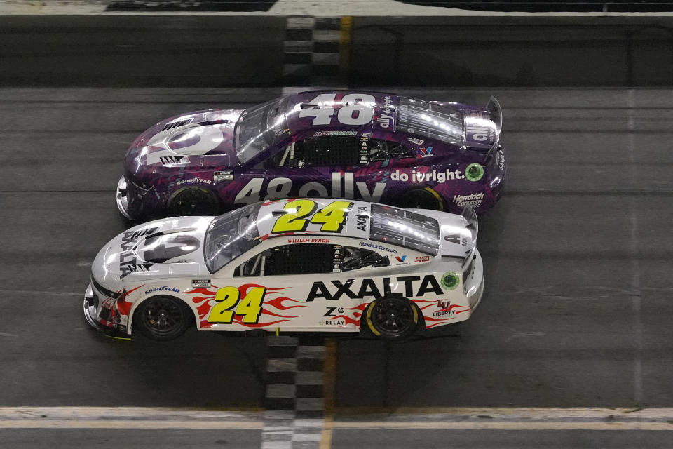 William Byron (24) crosses the finish line under caution to win NASCAR Daytona 500 auto race Monday, Feb. 19, 2024, at Daytona International Speedway in Daytona Beach, Fla. Riding along side Byron is Alex Bowman. (AP Photo/Chris O'Meara)