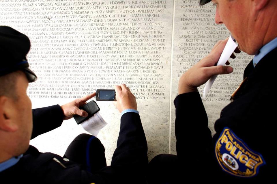 Police officers take photographs and engravings of the names of officers killed in the line of duty which are engraved on the marble walls of the National Law Enforcement Officers Memorial in Washington, D.C.