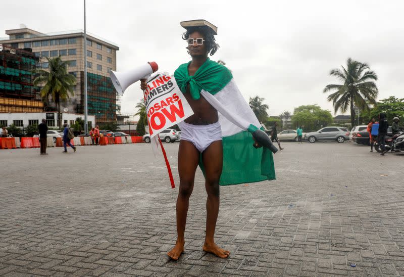 A demonstrator in underwear carries a hairdryer and a megaphone during a protest over alleged police brutality, in Lagos