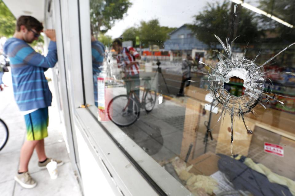 A man looks through a window with bullet holes at a deli that was one of nine crime scenes after series of drive -by shootings that left 7 people dead in the Isla Vista section of Santa Barbara