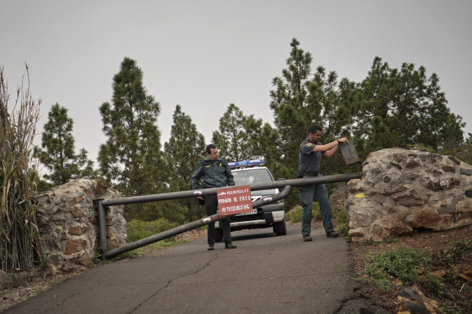 Members of the Spanish Civil Guard block the road leading to a cave at the base of the Teide volcano, where a mother and son were found Wednesday in Santa Cruz de Tenerife in the Canary Islands, Spain, Wednesday, April 24, 2019. The bodies of a German woman and her 10-year-old son were found in a cave in the Canary island of Tenerife, on Wednesday said the Civil Guard, adding that the boy's father, who was also German, had been arrested. (AP Photo/Andres Gutierrez)