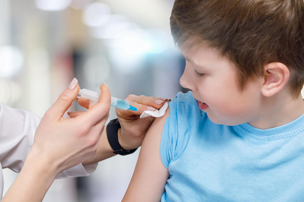 A closeup of a teenage child receiving a vaccine from a pediatrician with a syringe fullfilled with some substance. The concept of required preventive vaccination.