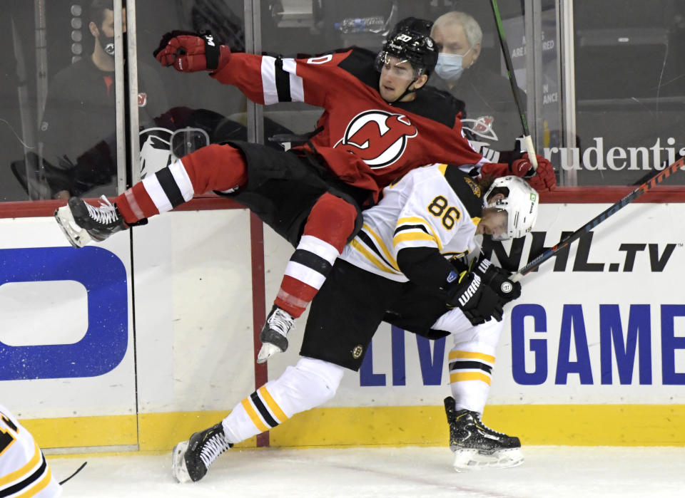 Boston Bruins defenseman Kevan Miller (86) ducks under a check by New Jersey Devils center Michael McLeod (20) during the second period of an NHL hockey game Thursday, Jan. 14, 2021, in Newark, N.J. (AP Photo/Bill Kostroun)