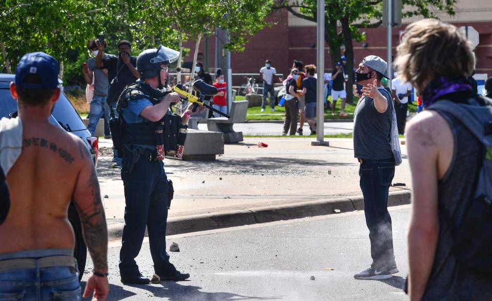 A St. Paul police officer armed with a less-lethal, paintball-style weapon faces off with a protester in front of the Target store near the intersection of University Avenue West and Hamline Avenue North Thursday, May 28, 2020, in St. Paul, Minnesota.