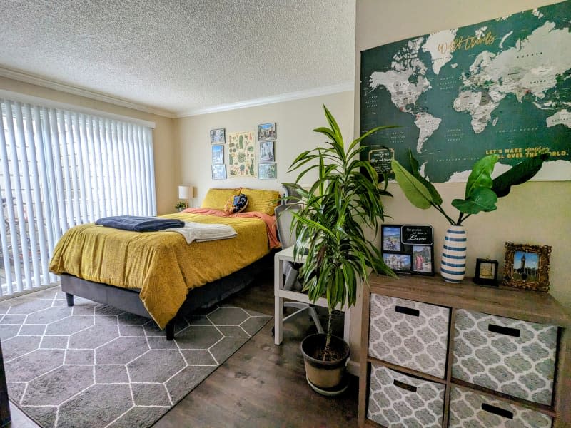 Beige bedroom with bed with gold bedding, plants, and neutral tones