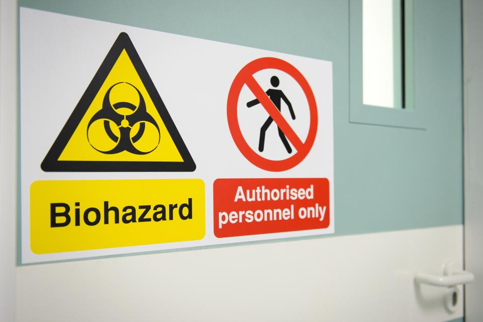 A sign warns of the biohazard threat outside a secure biolab facility.