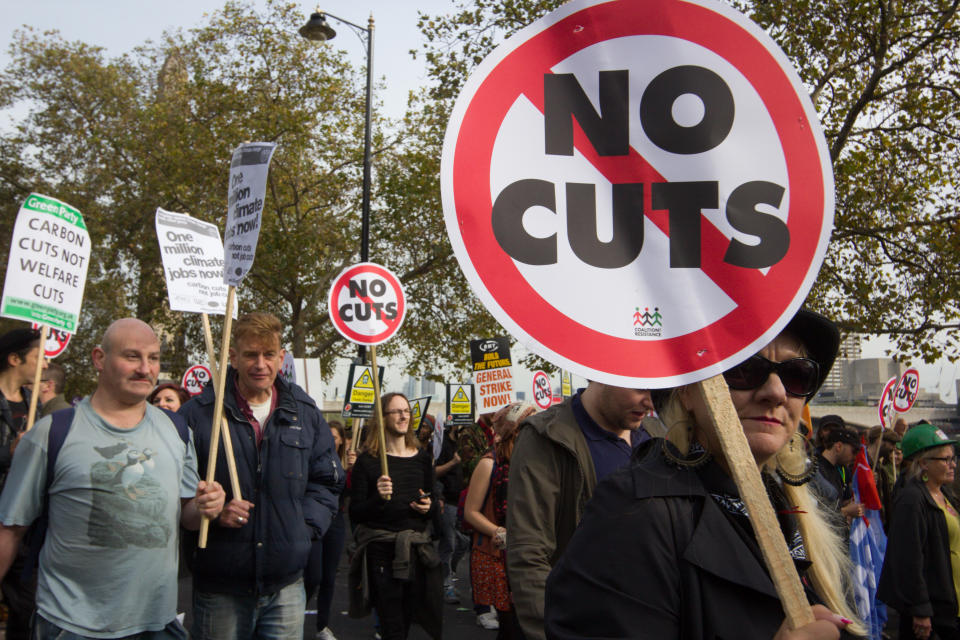 "London, England - October 20, 2012: Protesters march against David Cameron's Coalition Government spending cuts that are taking place in the UK public sector. In the image, a woman is brandishing a placard reading 'No Cuts'"