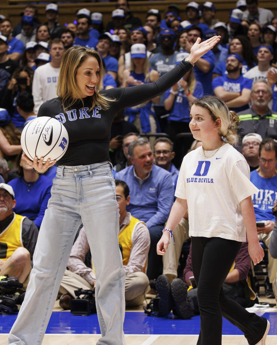 Marcelle Scheyer, left, wife of Duke coach Jon Scheyer, leads Samantha DiMartino onto the court at Cameron Indoor Stadium during a timeout in an NCAA college basketball game between Duke and Louisville as an honoree of the Scheyer Family Kid Captain Program, which recognizes patients and families of Duke Children's Hospital, in Durham, N.C., Wednesday, Feb. 28, 2024. (AP Photo/Ben McKeown)