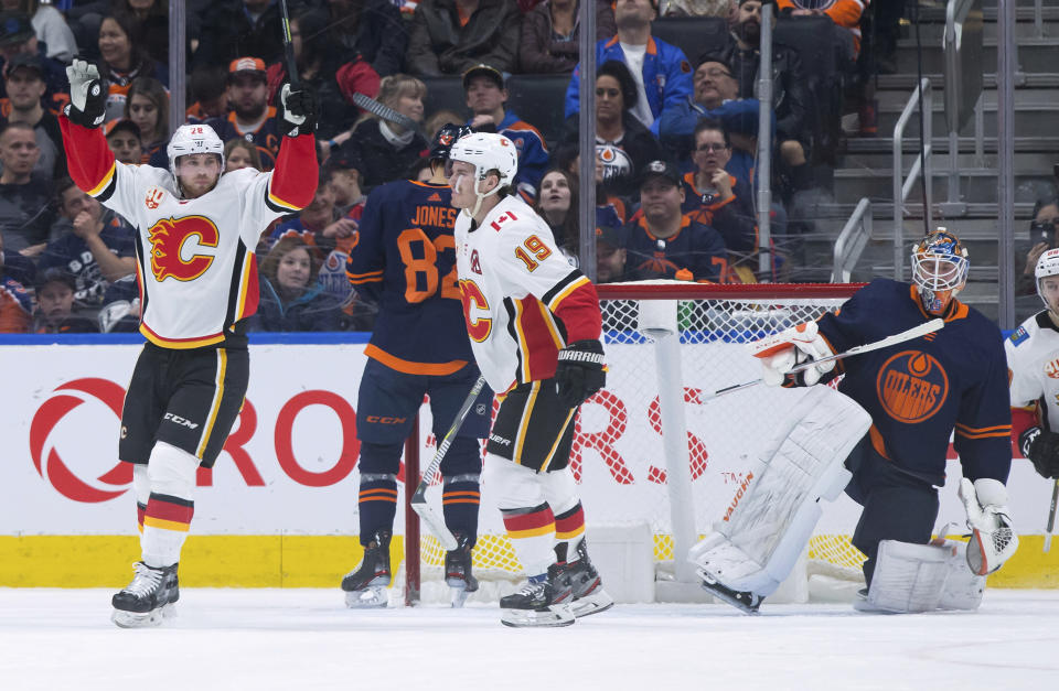 Calgary Flames' Elias Lindholm, left, of Sweden, and Matthew Tkachuk (19) celebrate Lindholm's goal against Edmonton Oilers goalie Mikko Koskinen, right, of Finland, during the second period of an NHL hockey game Friday, Dec. 27, 2019, in Edmonton, Alberta. (Darryl Dyck/The Canadian Press via AP)