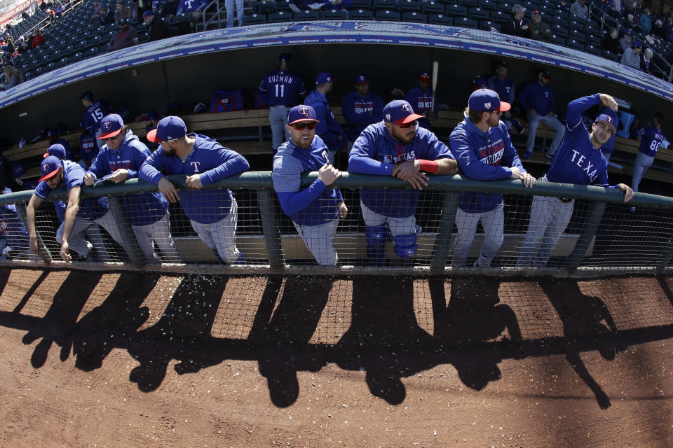 Texas Rangers players wait in the dugout before a spring training baseball game against the Kansas City Royals Saturday, Feb. 23, 2019, in Surprise, Ariz. (AP Photo/Charlie Riedel)