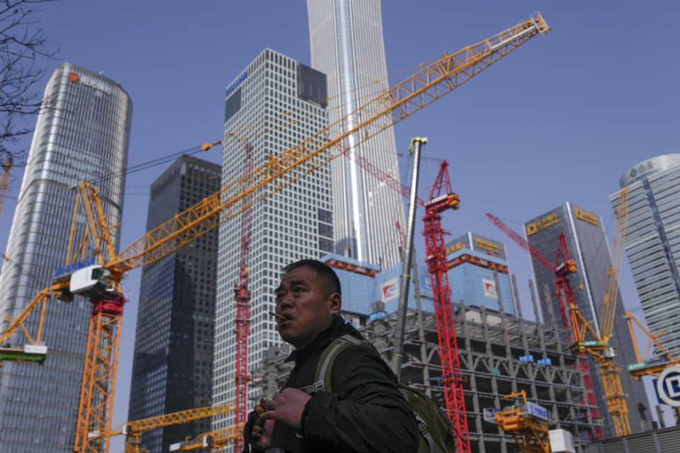 A man smokes as he walks by a construction site near office buildings in the Central Business District in Beijing on Saturday, March 2, 2024. One burning issue dominates as the 2024 session of China's legislature gets underway this week: the economy. The National People's Congress annual meeting, which opens Tuesday, is being closely watched for any signals on what the ruling Communist Party might do to re-energize an economy that is sagging under the weight of expanded government controls and the bursting of a real-estate bubble. (AP Photo/Andy Wong)