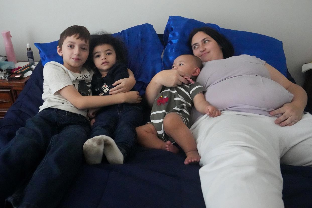 Rebecca Adamson tests her new bed with children, from left, Leon Adamson, Keiko Watkins and Lucas Watkins. Donations, including beds from Factory Mattress, and a matching donation from the Sheth family have helped raise almost $1.4 million for local nonprofits and their featured Season for Caring families, including the Adamson Watkins family.