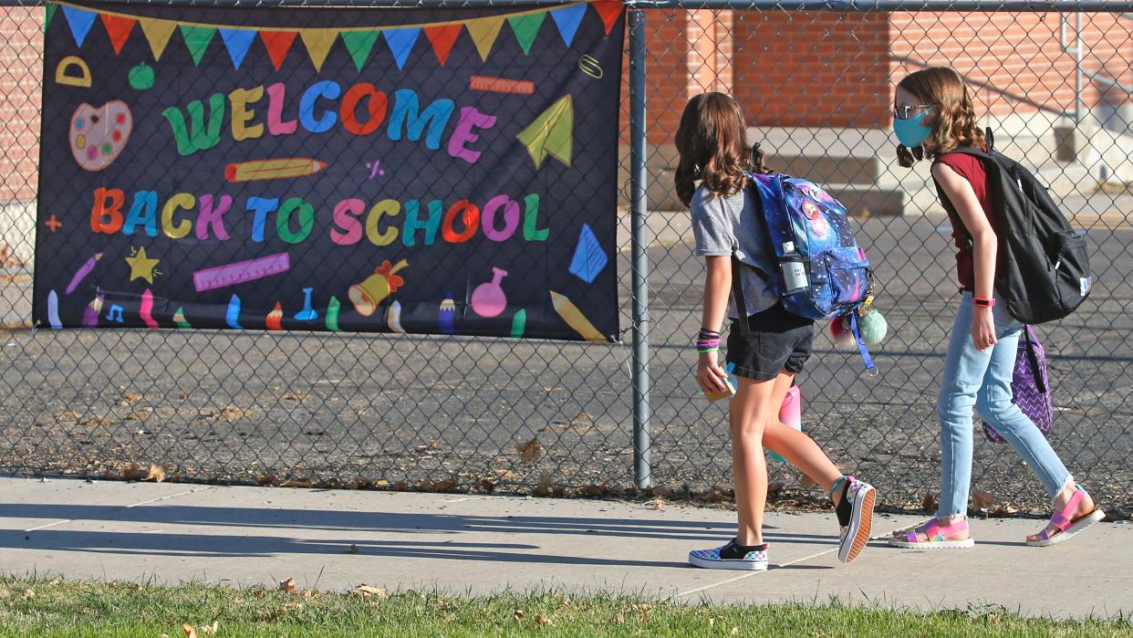 Cimmie Hunter, left, and Cadence Ludlow, both 6th graders, arrive at Liberty Elementary School during the first day of class on Monday, Aug. 17, 2020, in Murray, Utah. Murray City School District opened its doors Monday, offering its 6,300 students a choice among in-person learning, hybrid instruction and distance learning.