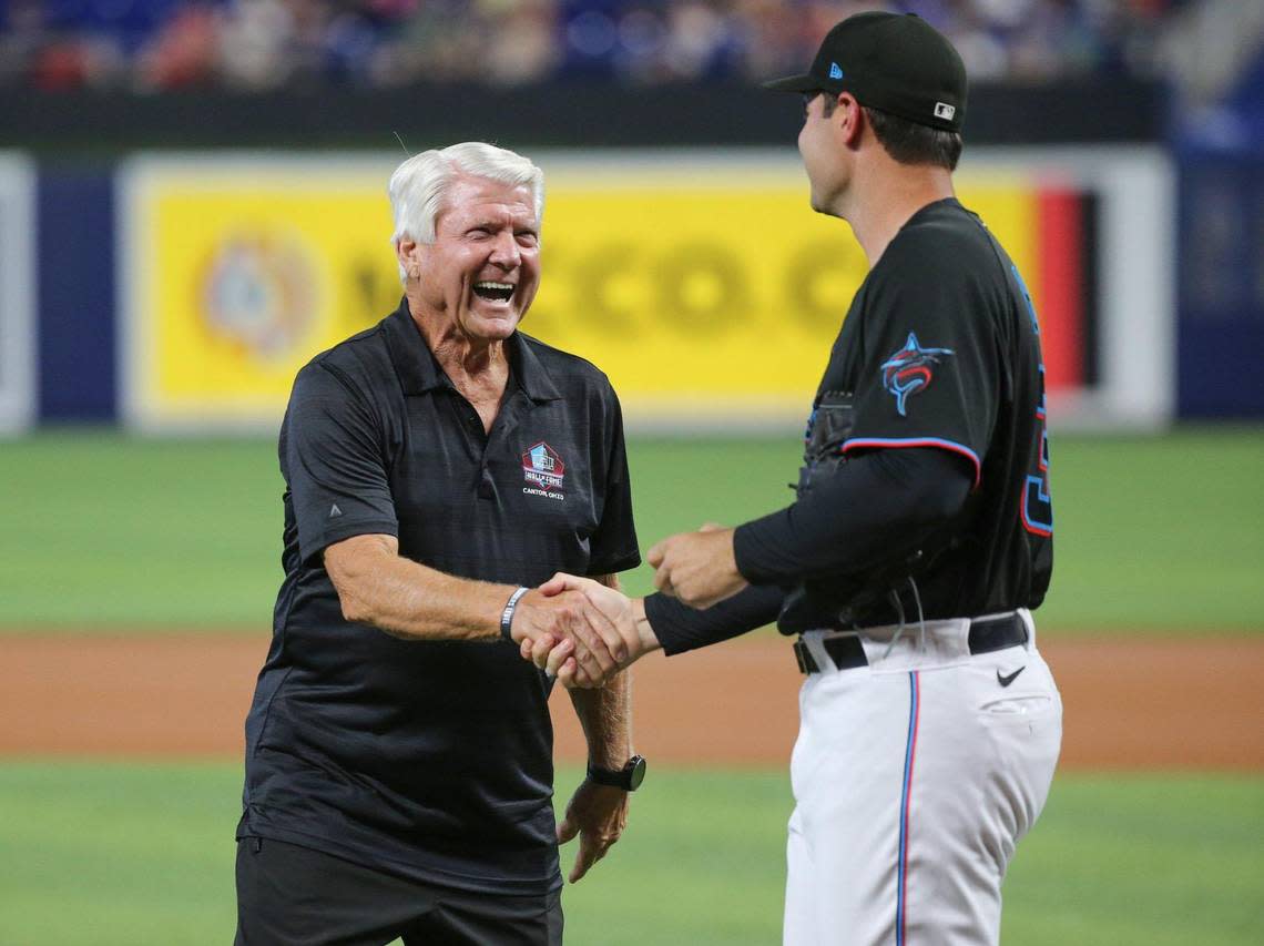 Pro Football Hall of Fame coach Jimmy Johnson is greeted by Richard Bleier (35) after Johnson throws the games first pitch at loanDepot Park in Miami on Saturday, August 13, 2022.