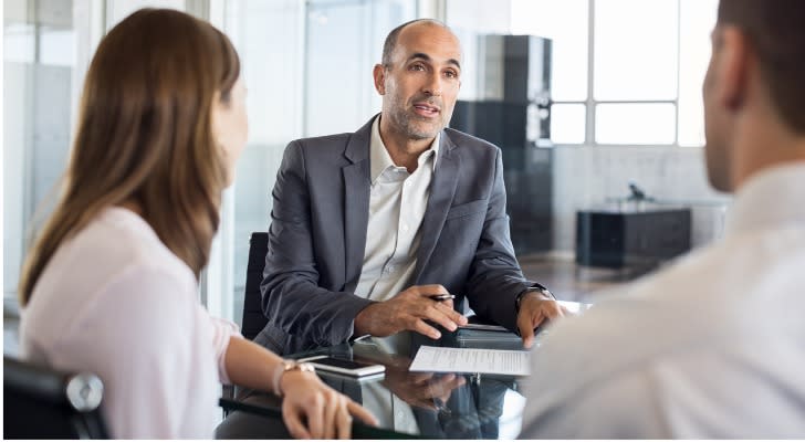 A financial advisor meets with a pair of clients in his office.