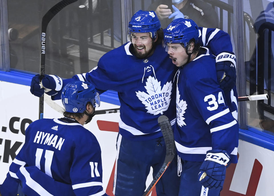 Toronto Maple Leafs center Auston Matthews (34) celebrates his goal with teammates Justin Holl (3) and Zach Hyman (11) after scoring against the Columbus Blue Jackets during second period NHL Eastern Conference Stanley Cup playoff action in Toronto on Tuesday, Aug. 4, 2020. (Nathan Denette/The Canadian Press via AP)