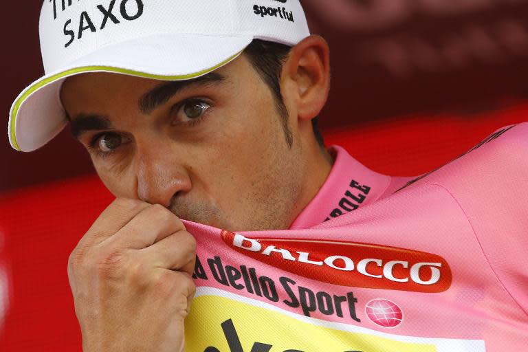 Spanish rider Alberto Contador kisses the pink jersey of overall leader on the podium of the 16th stage of the 98th Giro d'Italia on May 26, 2015