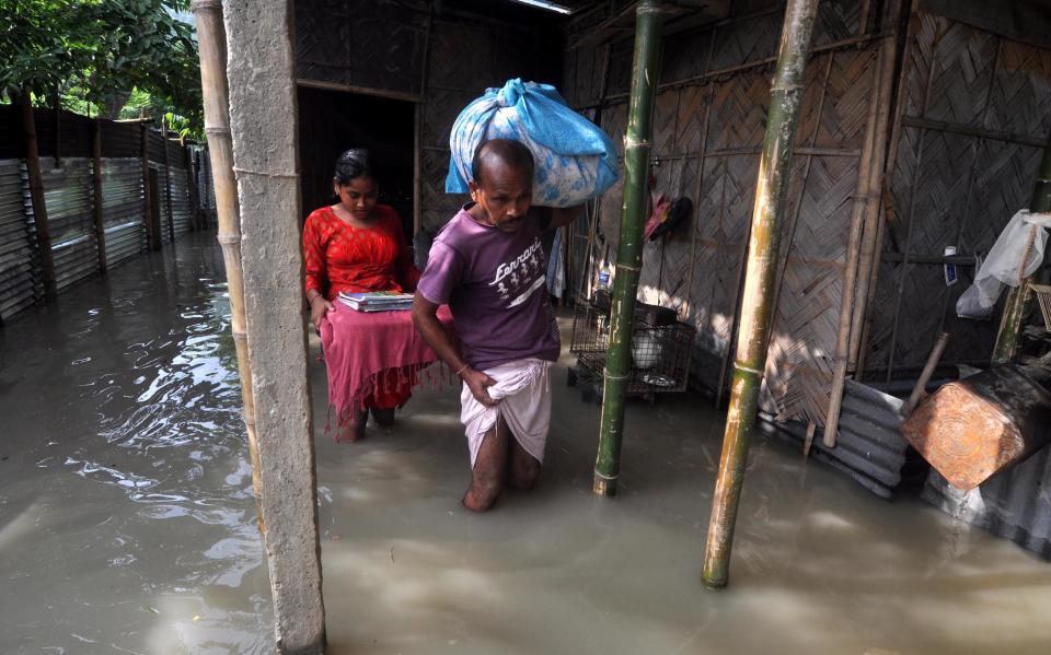 Villagers move to a safer place from the flooded area of Hatisela in Kamrup district of Assam. (Photo credit should read Anuwar Ali Hazarika/Barcroft Media via Getty Images)