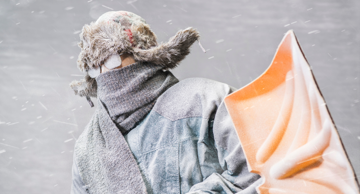 man in parka and furry hat holding shovel in blizzard 