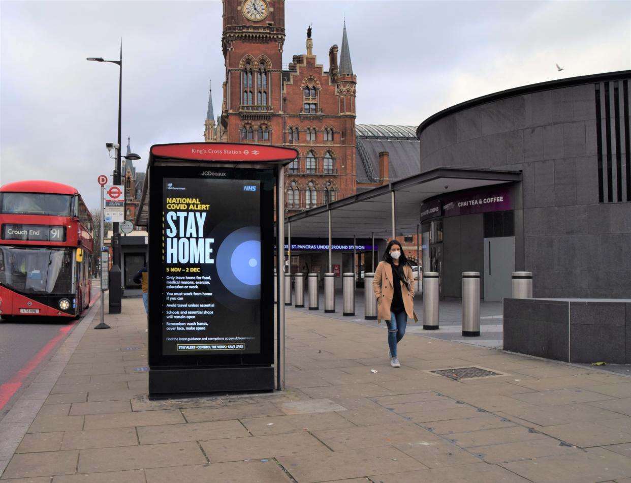 LONDON, UNITED KINGDOM - 2020/11/21: A woman wearing a face mask as a precaution walks past a Stay Home sign in King's Cross. (Photo by Vuk Valcic/SOPA Images/LightRocket via Getty Images)