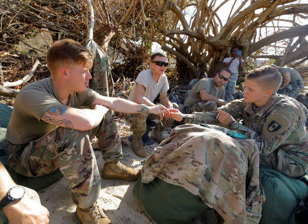 Soldiers from the Army's 602nd Area Support Medical Company share a light for a cigarette while waiting for transport on a Navy landing craft during their evacuation in advance of Hurricane Maria, in Charlotte Amalie, St. Thomas, U.S. Virgin Islands September 17, 2017. REUTERS/Jonathan Drake