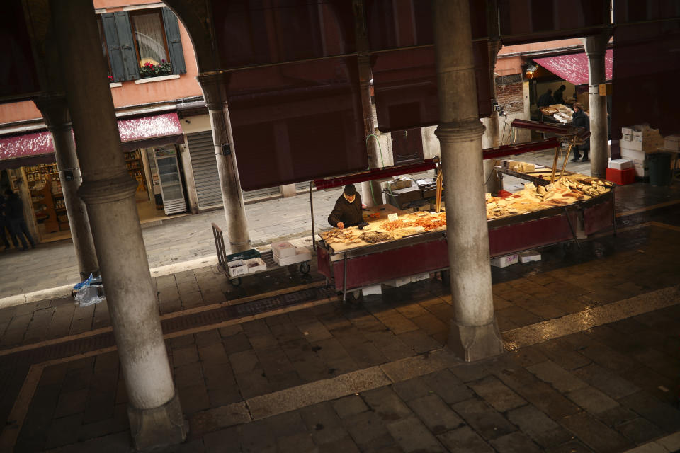 A fishmonger waits for clients in a barely empty street food market in Venice, Saturday, Feb. 29, 2020. A U.S. government advisory urging Americans to reconsider travel to Italy due to the spread of a new virus is the "final blow" to the nation's tourism industry, the head of Italy's hotel federation said Saturday. Venice, which was nearing recovery in the Carnival season following a tourist lull after record flooding in November, saw bookings drop immediately after regional officials canceled the final two days of celebrations this week, unprecedented in modern times. (AP Photo/Francisco Seco)
