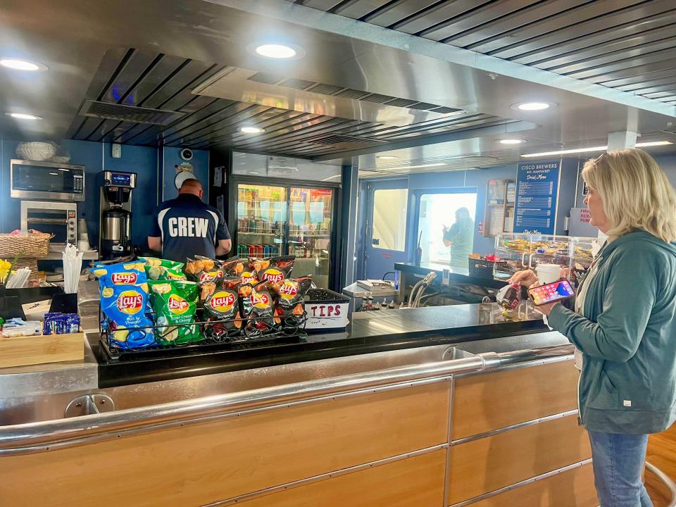 A snack bar with a woman wearing a green sweatshirt standing at the counter. The counter holds several Lay's chips.