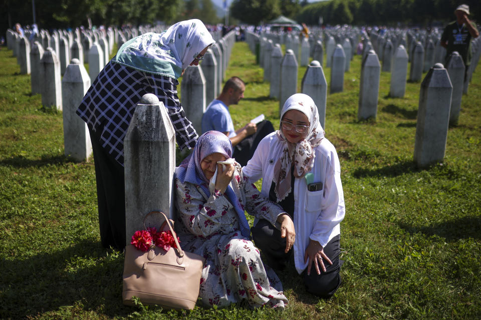 A Bosnian muslim women mourn next to the grave of their relative, victim of the Srebrenica genocide, at the Srebrenica Memorial Centre, in Potocari, Bosnia, Thursday, July 11, 2024. Thousands gather in the eastern Bosnian town of Srebrenica to commemorate the 29th anniversary on Monday of Europe's only acknowledged genocide since World War II. (AP Photo/Armin Durgut)